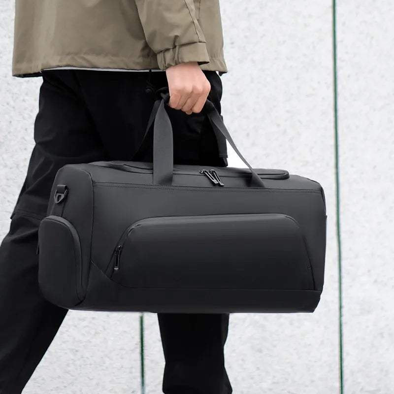 Person holding a black duffel bag against a light gray background