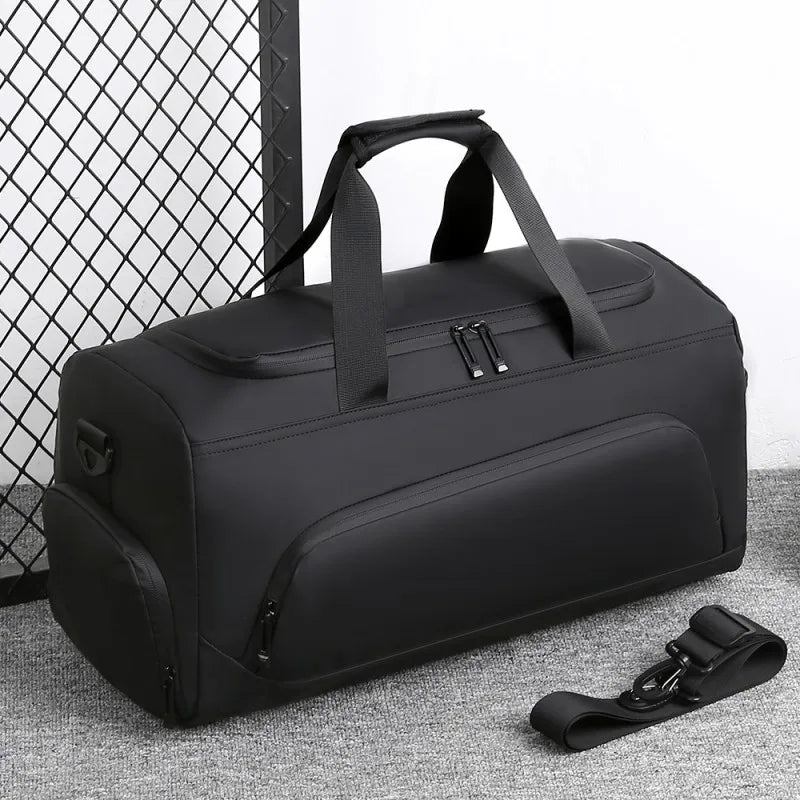Black duffel bag with a strap on a textured surface with a wire mesh background
